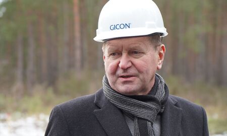 Der Landrat von Oberspreewald-Lausitz, Siegurd Heinze, steht mit Bauhelm auf der Baustelle. Er trägt Schal und Winterjacke.