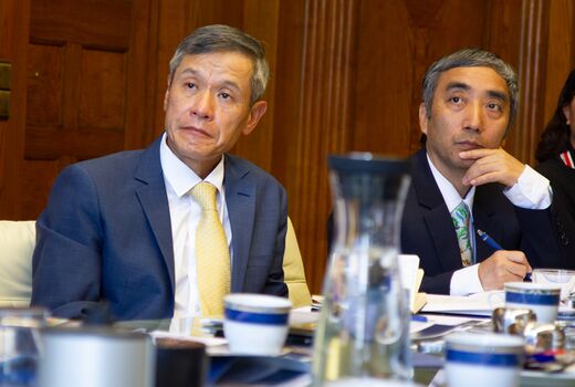 Man with tie at conference table watches presentation